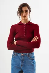 Top de tejido de punto acanalado color bordó, de manga larga y cuello polo con botones frontales.