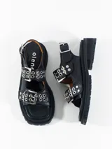 Sandalias negras de cuero con plataforma y hebillas plateadas ajustables en el empeine y el tobillo.