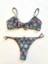 Conjunto de bikini verde con estampado de conchas rosadas. El corpiño es con aro y la bombacha es de atar.
