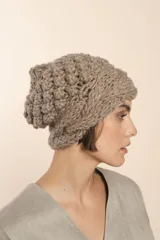 Gorro tejido a mano con hilado rueca, color beige. Presenta variedad de texturas: punto garbanzo y guarda con diseño de trenzas.