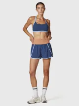 Short deportivo 2 en 1 de color azul con calza interior incorporada. Presenta una cintura ancha elástica en color tostado, ribetes en color celeste y bolsillos funcionales. Confeccionado con tecnología de secado rápido y materiales reciclados.