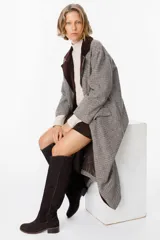 Bota de caña alta confeccionada en cuero color chocolate, con diseño de pespuntes decorativos a lo largo de la caña y taco bajo cuadrado.