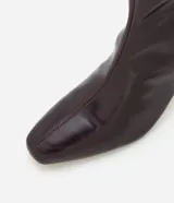 Bota de caña media Satinato, confeccionada en poliuretano con acabado brillante. Presenta diseño ajustado al tobillo, punta cuadrada y tacón fino de 6 cm. Incluye cierre lateral discreto.