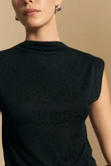 Top sin mangas de tejido texturizado con brillo integrado, color beige dorado, con cuello alto y hombros levemente estructurados.