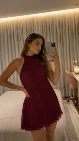 Vestido corto de color bordó con diseño plisado, cuello alto y espalda descubierta.