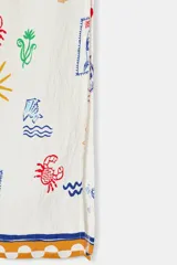 Vestido largo estilo túnica de color crudo con estampado multicolor de motivos marinos y mediterráneos. Presenta cuello con volante, cierre frontal con botones, manga larga y cordón ajustable en el cuello con abalorios.
