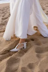 Sandalia de cuero color bordó, con acabado charolado, punta fina y tacón cuadrado de 5 cm. Presenta una tira en forma de T sobre el empeine y una correa con hebilla alrededor del tobillo.