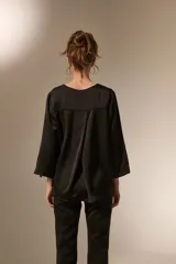 Blusa de satén color bordó con cuello en V y mangas tres cuartos. Presenta un diseño holgado con un pliegue central en el frente.