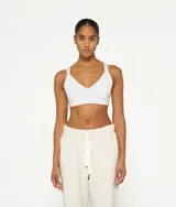 Top deportivo blanco de algodón orgánico con tirantes cruzados en la espalda y logo de minirayas.