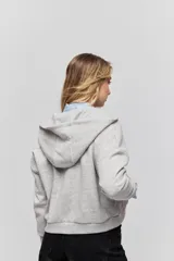 Campera tostada de calce relajado con capucha, cierre frontal, bolsillos laterales y detalles de tachas metálicas.