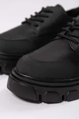 Zapato acordonado de cuero negro con suela track.