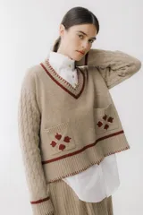 Sweater color borgoña con escote en V, mangas largas con diseño de ochos, bolsillos frontales y bordados con forma de hojas.