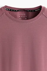 Remera deportiva de manga raglán y cuello redondo, color bordó, con diseño de tejido técnico texturizado y costuras planas, corte ajustado al cuerpo tipo muscle fit.