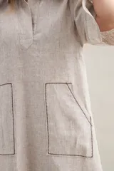Vestido largo lila de lino, con cuello camisero, mangas cortas, bolsillos frontales con costuras a contratono y aberturas laterales.