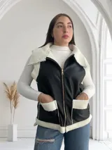 Chaleco negro de ecocuero con interior de corderito blanco, cierre frontal con cremallera y bolsillos laterales.