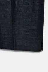 Pantalón de tiro medio confeccionado en tejido con lino, de corte recto y diseño clásico. Presenta bolsillos laterales, falsos bolsillos traseros de vivo, cierre frontal con cremallera y ganchos metálicos, y aberturas laterales en el bajo.