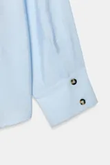 Camisa de cuello alto y manga larga, confeccionada en tejido satinado. Presenta un diseño con pliegue frontal decorativo con botón visible y cierre frontal con botones ocultos bajo solapa.