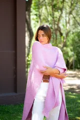 Ruana tejida color rosa con flecos en el borde inferior.