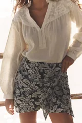 Short de tiro alto con detalle de nudo delantero y bordados florales perforados.