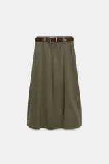 Falda midi tipo capa de tiro medio, confeccionada en mezcla de algodón color verde militar. Cuenta con cintura con trabillas, bolsillos de vivo en los laterales, cierre lateral con cremallera oculta y aplicación de cinturón marrón de estilo western con hebilla metálica grabada.