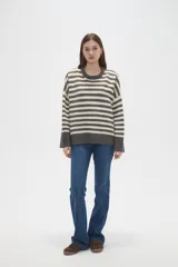 Sweater de punto con diseño de rayas horizontales en gris y beige, de corte holgado, cuello redondo a la base y mangas largas.