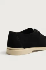 Zapato casual de cordones para hombre, confeccionado en piel con acabado serraje de color negro. Presenta detalle de bordón en el empeine, horma redonda y suela plana en contraste de color beige.