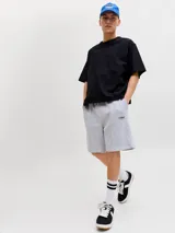 Bermuda deportiva gris melange de felpa, con calce relajado, tiro bajo, bolsillos laterales y pequeño estampado con texto en la pierna izquierda.