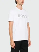Remera blanca de manga corta con cuello redondo y el logo "BOSS" estampado en el pecho con un patrón de puntos en tonos grises y negros.