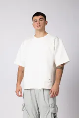Remera de corte oversize color blanco, con cuello redondo y manga corta. Presenta una etiqueta pequeña con logo en el dobladillo inferior.
