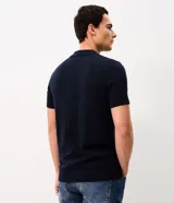 Polo de punto azul marino para hombre, confeccionada en algodón con textura de rayas verticales y patrón en zigzag, cuello polo con cierre frontal parcial y mangas cortas.