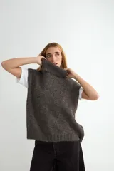 Chaleco de punto gris con cuello alto, diseño sin mangas y corte holgado.