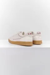 Zapatillas deportivas de cuero color blanco hueso con detalles bordados y suela color caramelo.