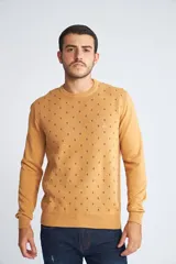 Sweater de punto color mostaza con cuello redondo y mangas largas. Presenta un estampado de pequeños motivos repetidos en contraste y un logo bordado en el pecho.
