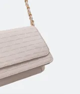 Bolso pequeño estructurado color negro, con textura capitoneada, asa de cadena y solapa frontal con botón a presión. Incluye divisor interno con cremallera.