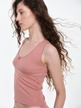 Musculosa de punto pointelle color gris melange, con escote redondo, detalle de picot en los bordes y una pequeña moña decorativa en el centro del pecho.