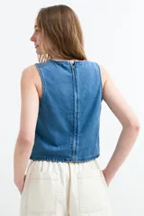 Top de denim sin mangas, color crudo, con cuello redondo y costura central visible.