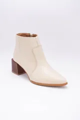 Botas cortas de cuero color beige, con punta fina y cierre lateral. Tienen un taco cuadrado de madera.