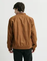 Campera tipo bomber de color marrón, confeccionada en tejido con textura similar a la gamuza, con cierre frontal completo, cuello redondo y puños elásticos.