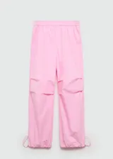 Pantalon estilo parachute de color rosado, con cintura elástica y bajos ajustables mediante cordones. Presenta un diseño holgado con bolsillos laterales.