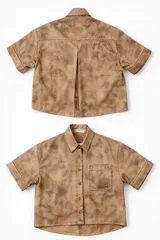 Camisa oversized de manga corta confeccionada en algodón, con diseño cropped y calce amplio. Posee cuello clásico, cierre frontal con botones, un bolsillo de parche en el pecho y detalle de pliegue en la espalda. Presenta un acabado estampado tipo tie-dye en tonos marrones.