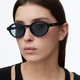 Lentes de sol con montura redonda de color negro y cristales polarizados en tono azul. Presentan un diseño retro con protección UV400 y recubrimiento resistente a rayaduras.