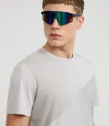 Remera deportiva de hombre, color gris claro, con cuello redondo y manga corta. Presenta un sutil efecto degradado o panel de color más claro en la zona del pecho.