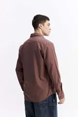 Camisa de manga larga color azul marino con textura, cuenta con cuello clásico, cierre frontal con botones y un bolsillo en el pecho.