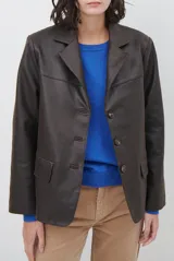 Blazer de cuero color marrón, con corte entallado, cuello con solapas, cierre frontal con botones y bolsillos laterales con solapa.