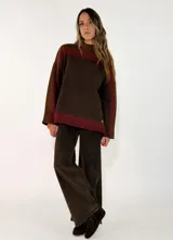 Sweater de punto con diseño de bloques de color en tonos marrón, chocolate y bordó, cuello alto y mangas largas con corte holgado.
