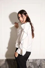 Camisa blanca con volados con terminación de hilo negro en cuello, mangas y frente.