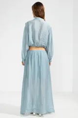 Falda larga hasta el tobillo color celeste, confeccionada en tejido arrugado liviano con cintura elástica.