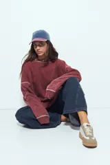 Buzo con capucha de calce relajado, confeccionado en tela con efecto lavado desgastado. Presenta costuras a la vista en color contrastante y un bolsillo frontal tipo canguro.