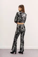 Pantalón de terciopelo negro con estampado floral en plateado, de corte acampanado.