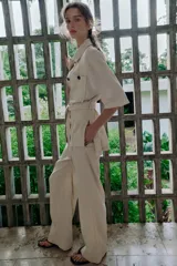 Pantalón de tiro medio confeccionado en lino color beige, de pernera recta con nervios marcados en el delantero. Posee bolsillos frontales, falsos bolsillos de vivo en la espalda y cierre frontal con cremallera, botón interior y gancho.